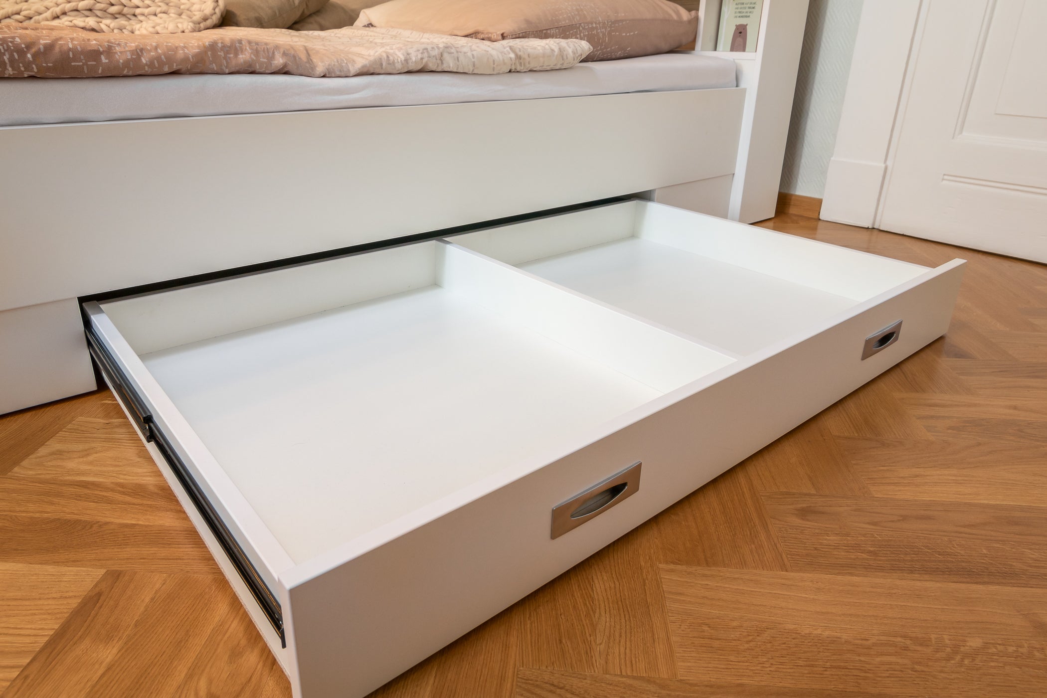 Weißer Bettkasten ausgezogen auf Schienen an Familienbett