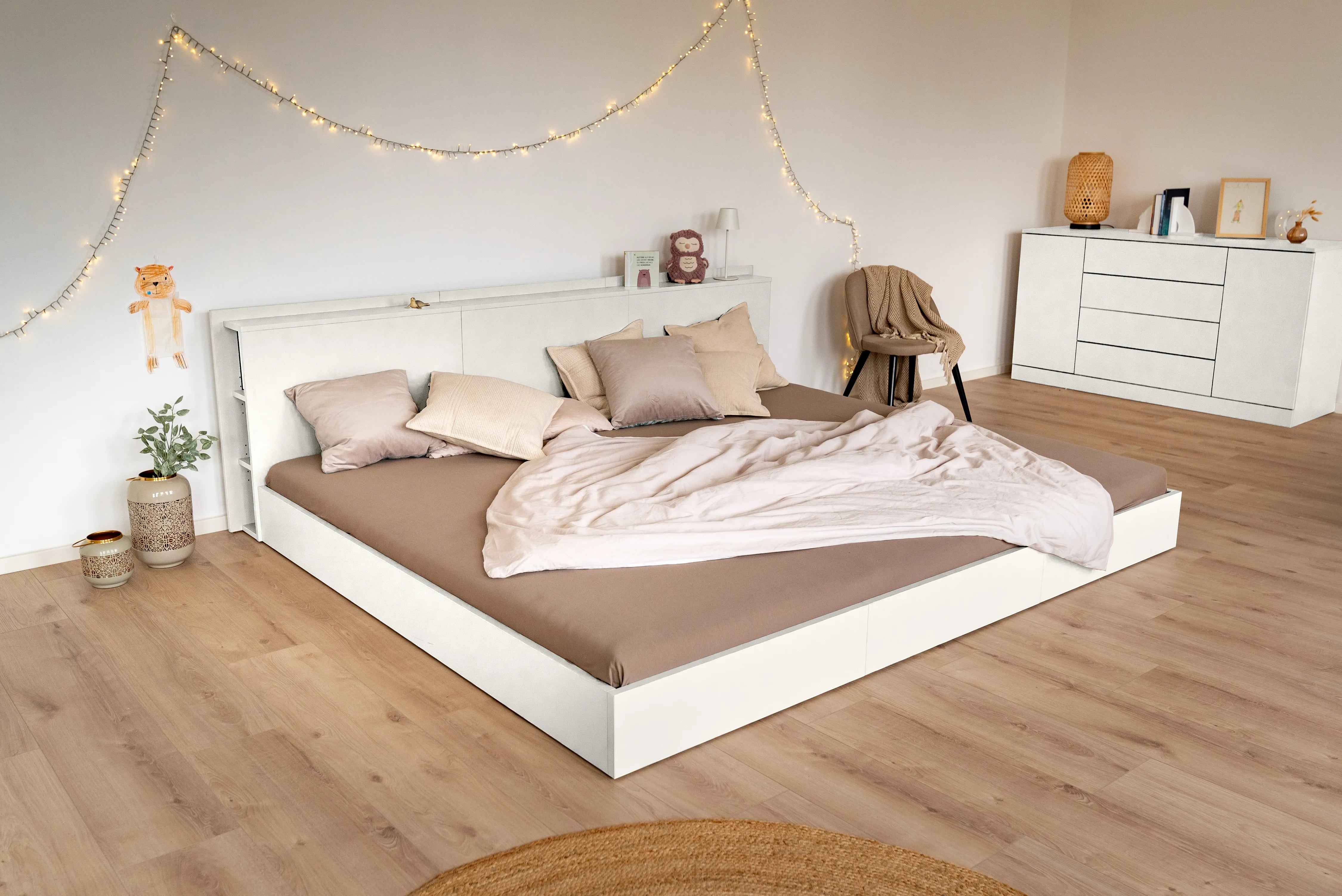 Familienbett in Weiß mit Spannbettlaken in braun und gemütlichen Kissen